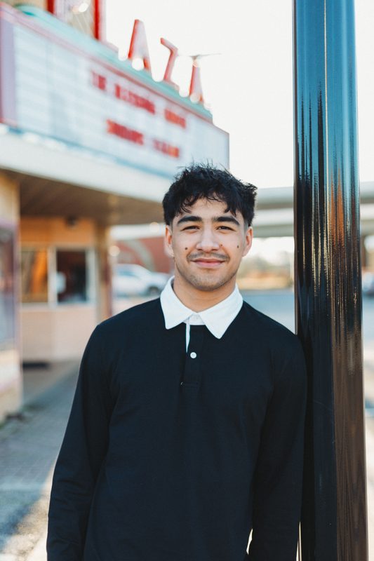 Senior beside the Plaza sign