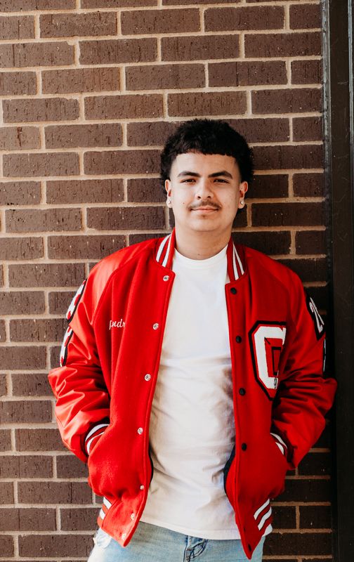 Senior in a letter jacket against brick