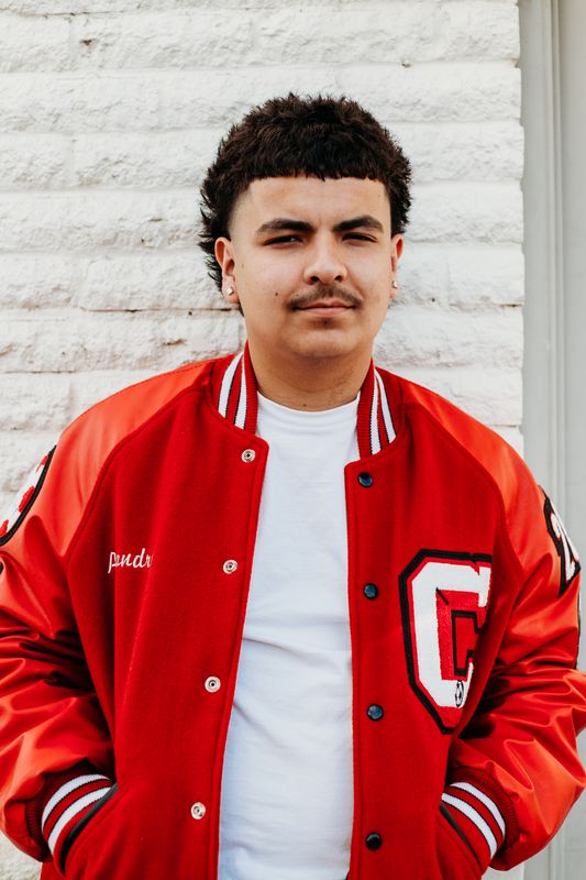 Senior in a letter jacket against white brick