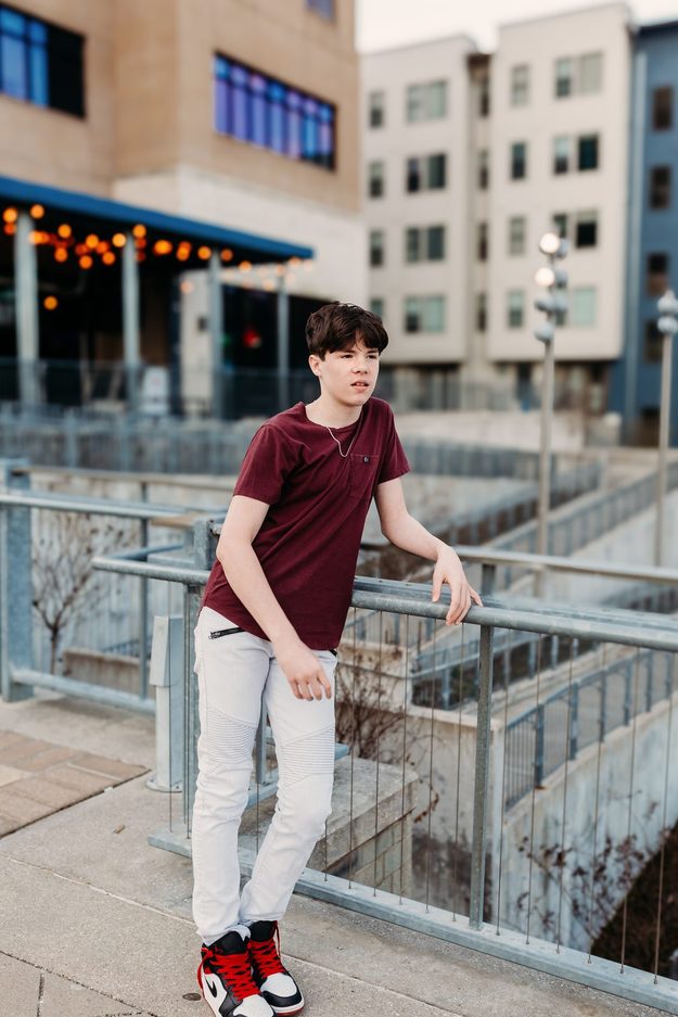 Senior at a rail under string lights