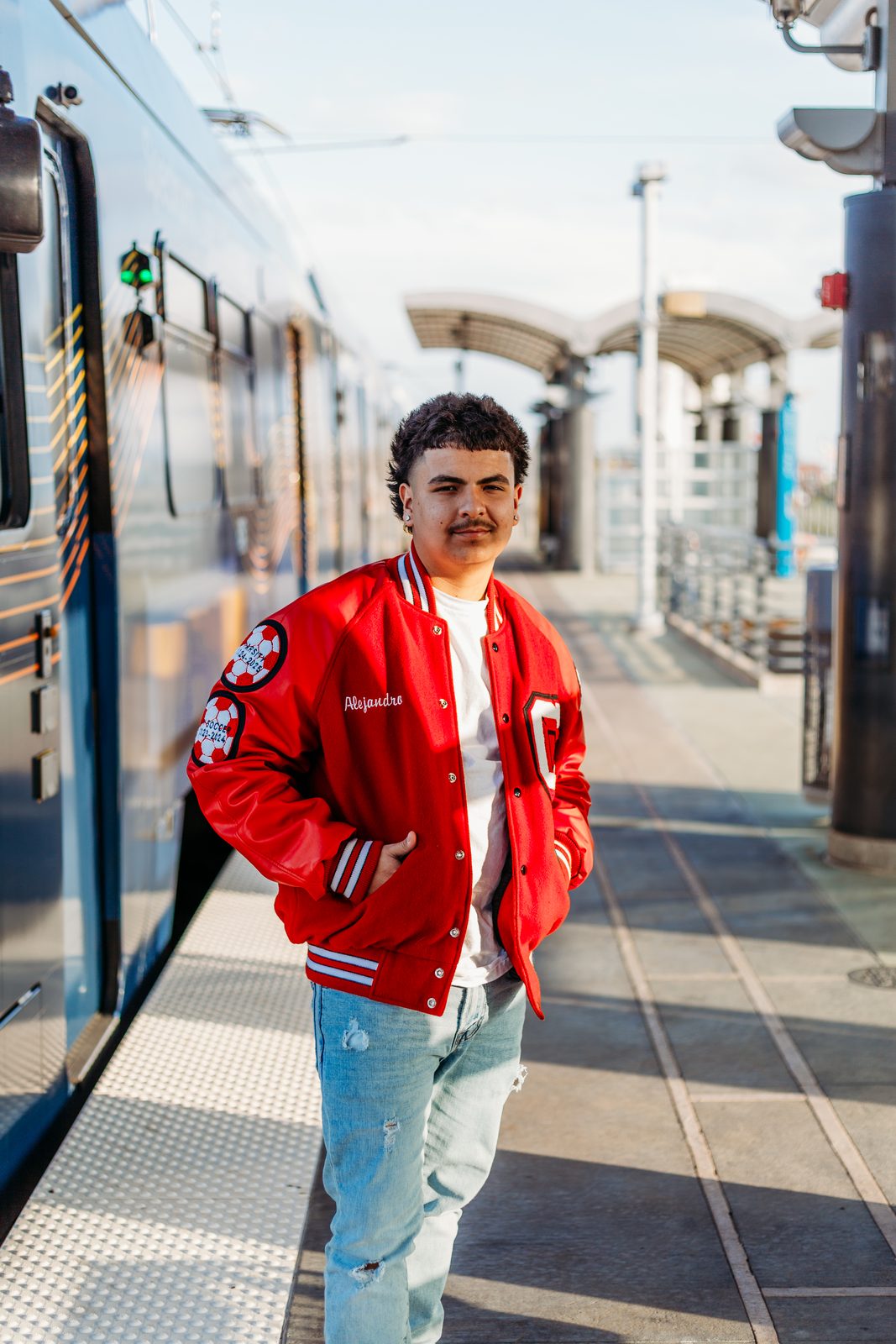 Senior in a red letter jacket at the rail platform