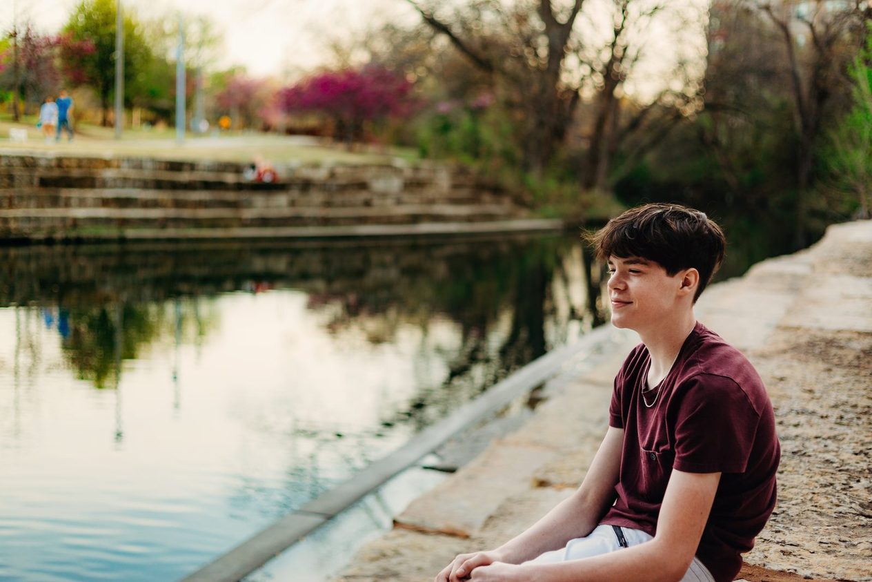Senior sitting on a ledge above the water